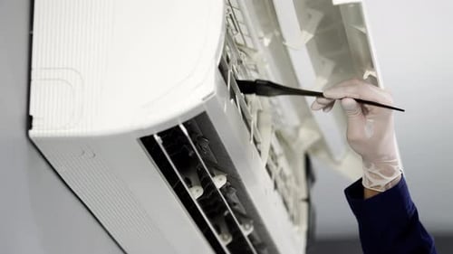 close up technician service using brush to cleaning the air conditioner indoors