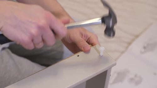 Mann mit einem Hammer baut Möbel zusammen
