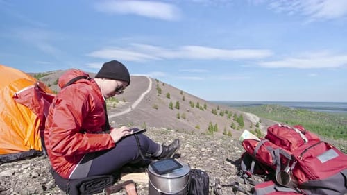 Hiker Using Tablet at Scenic Mountain Campsite