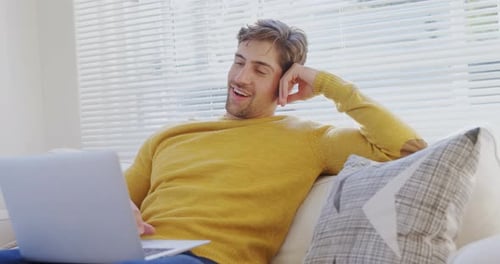 Young Adult Using Laptop on Couch at Home