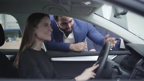 Woman Smiles with Car Salesman in Dealership