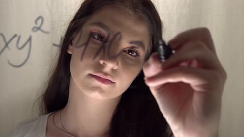 Young Adult Writes Math Equation on Glass