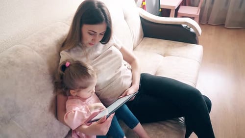 Woman and Child Using Tablet on Couch