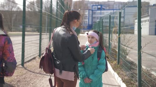 Mother and Daughter in Protective Masks Go to School
