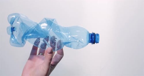 Hand Holds a Crushed Plastic Bottle