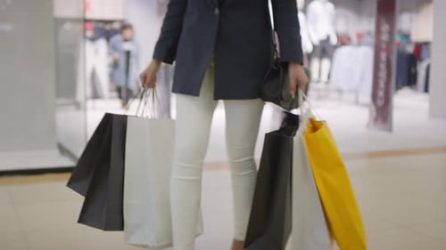 Beine einer Frau, die mit vielen Taschen durch das Einkaufszentrum geht