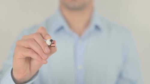 Man Writes Economics on Clear Surface with Marker