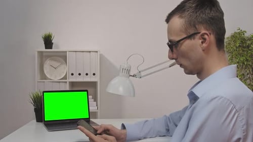 Back View of Businessman Look Green Screen Laptop in Office