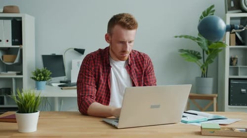 Tired Ginger-haired Guy Working with Computer in Office Feeling Headache