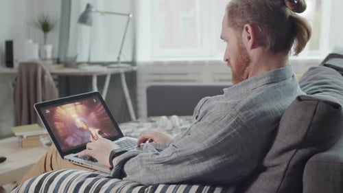 Man Playing Video Game on Laptop at Home