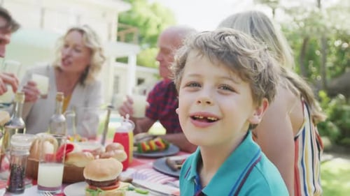 Portrait of happy caucasian boy having dinner with family in garden
