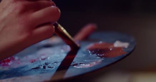 Artist Mixing Red and Brown Paint on Palette