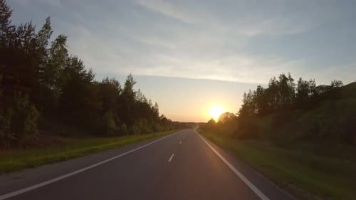 Fahren Sie bei Sonnenuntergang auf einer Landstraße