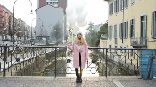 young beautiful woman posing looking camera with white balloon outdoor city