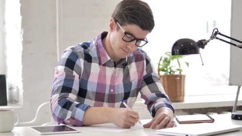 Man Writing at Desk in Office