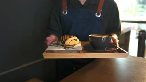 Garçom de homem asiático 4K servindo café com leite e padaria para cliente mulher na mesa do café