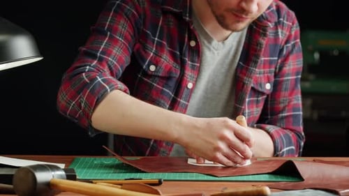 Man Tailor Cutting Artificial Leather with Stencil Closeup