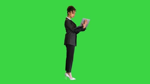 Black Businesswoman Standing with a Laptop on a Green Screen Chroma Key
