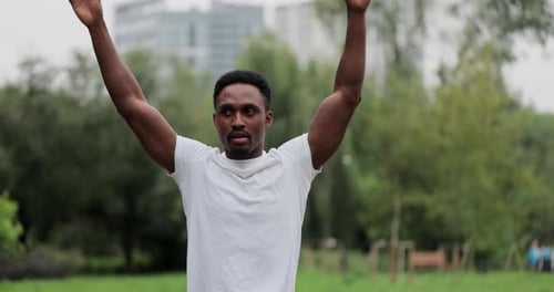 Sporty African Man with Warm Up By Stretching Arms Before Running in City Park