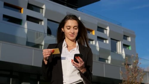 Smiling Woman Holds Credit Card and Smartphone