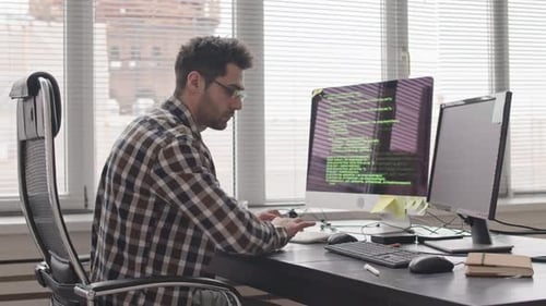 Programmer Writing Program Code on Computer