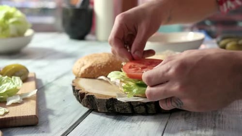 Adult Prepares Delicious Hamburger with Toppings