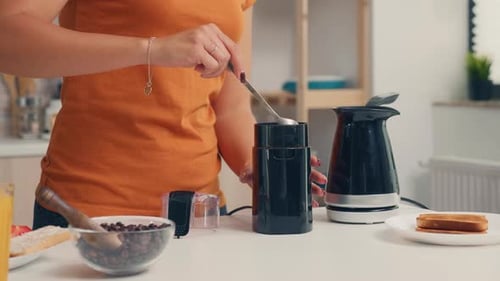Woman Making Coffee in Kitchen at Breakfast