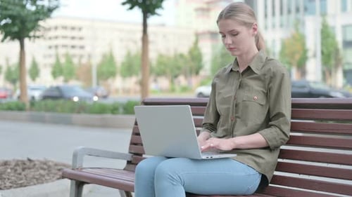 Woman Works on Laptop Outdoors on Park Bench