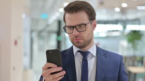 Man in Suit Focused on Smartphone