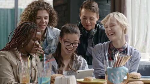 Teens Laughing Looking at Tablet Together Indoors