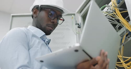 Technician Inspecting Servers with Laptop in Data Center