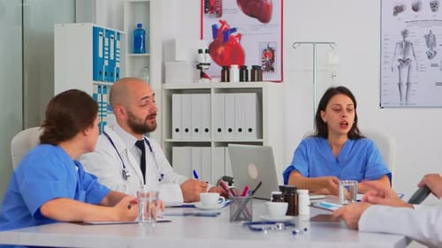 Team of Doctors During Brainstorming Sitting at Desk in Meeting Medical Office
