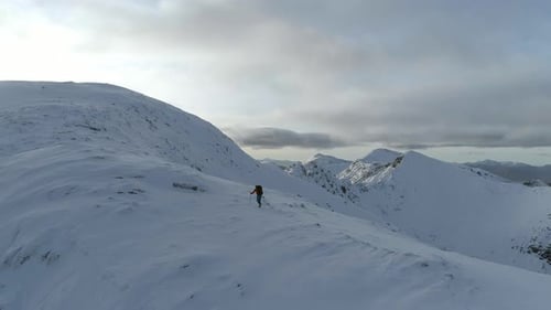 Mountain Climber Climbing Towards the Summit of a Snowy Mountain