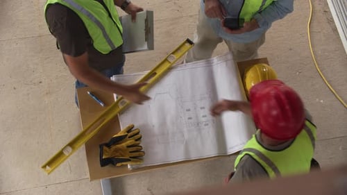Três trabalhadores da construção civil apertando as mãos sobre plantas, tiro no ar