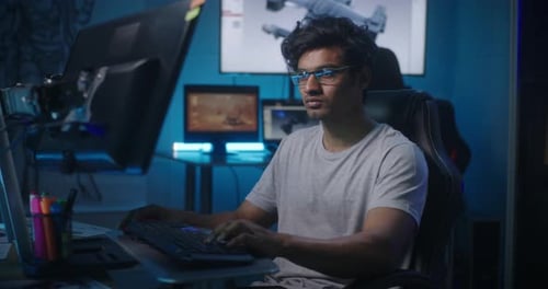 Young Adult Typing at Computer in Dark Room