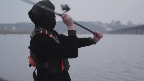 Porträt Junger selbstbewusster Fischer am frühen Morgen beim Spinnfischen im Fluss in der Nähe der Stadt