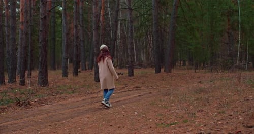 Woman Walks in the Autumn Forest Walks Along a Forest Path and Looks Around