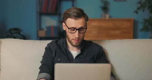 Man Works on Laptop in Home Living Room
