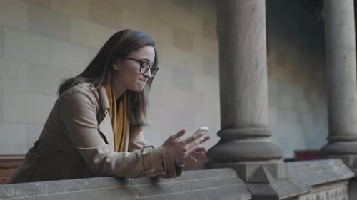 Woman Using Phone on Balcony Overlooking City