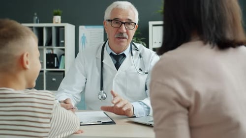 Senior Medic Talking To Family Mother and Son Discussing Child's Health in Office