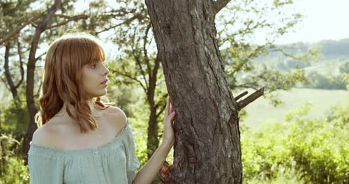 Young Woman Pauses By Tree In Sunny Rural Setting