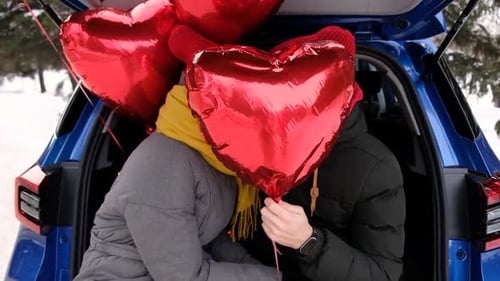 Romantic Couple With Heart Balloons in Car Trunk