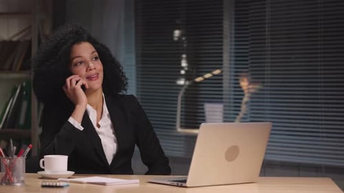 Smiling Woman Talking on Phone at Office Desk