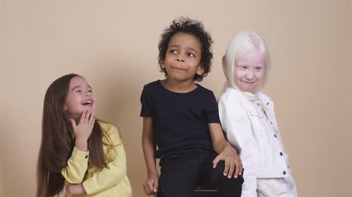 Three Smiling Children Posing in Front of Backdrop