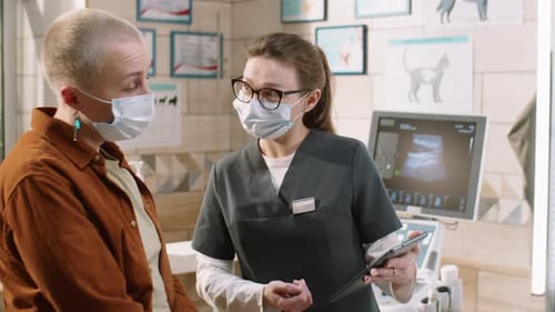 Vet Using Tablet and Talking with Client in Clinic