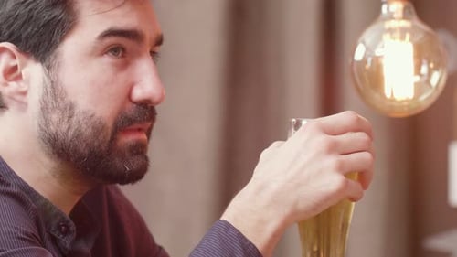 Bel homme barbu boit de la bière et parle au barman