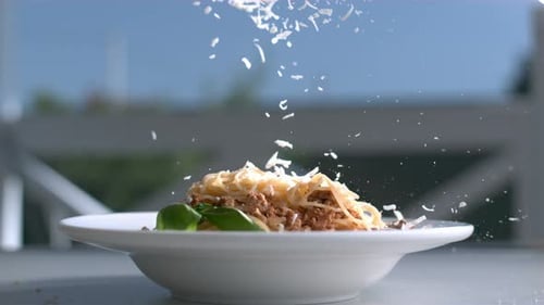 Parmesan Cheese Falling on Spaghetti Bolognese with Basil