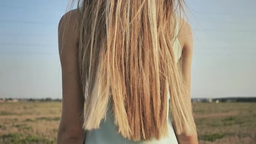 Young Woman Walking Through Field With Long Hair