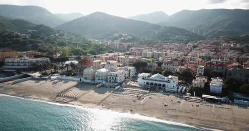Stadt, Berge und ein Sandstrand neben dem Mittelmeer. Drohnen-Luftaufnahme bei Sonnenuntergang, ital
