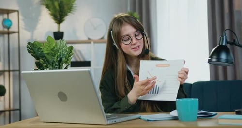 Mujer independiente con auriculares que se sienta frente a una computadora portátil durante una videoconferencia